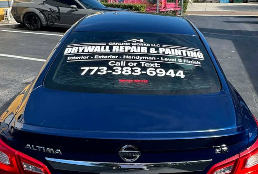 Dark blue Nissan Altima with white Oakline Works LLC drywall repair and painting vinyl lettering on the rear window, installed by BAPS Signs & Wraps in Oldsmar, FL