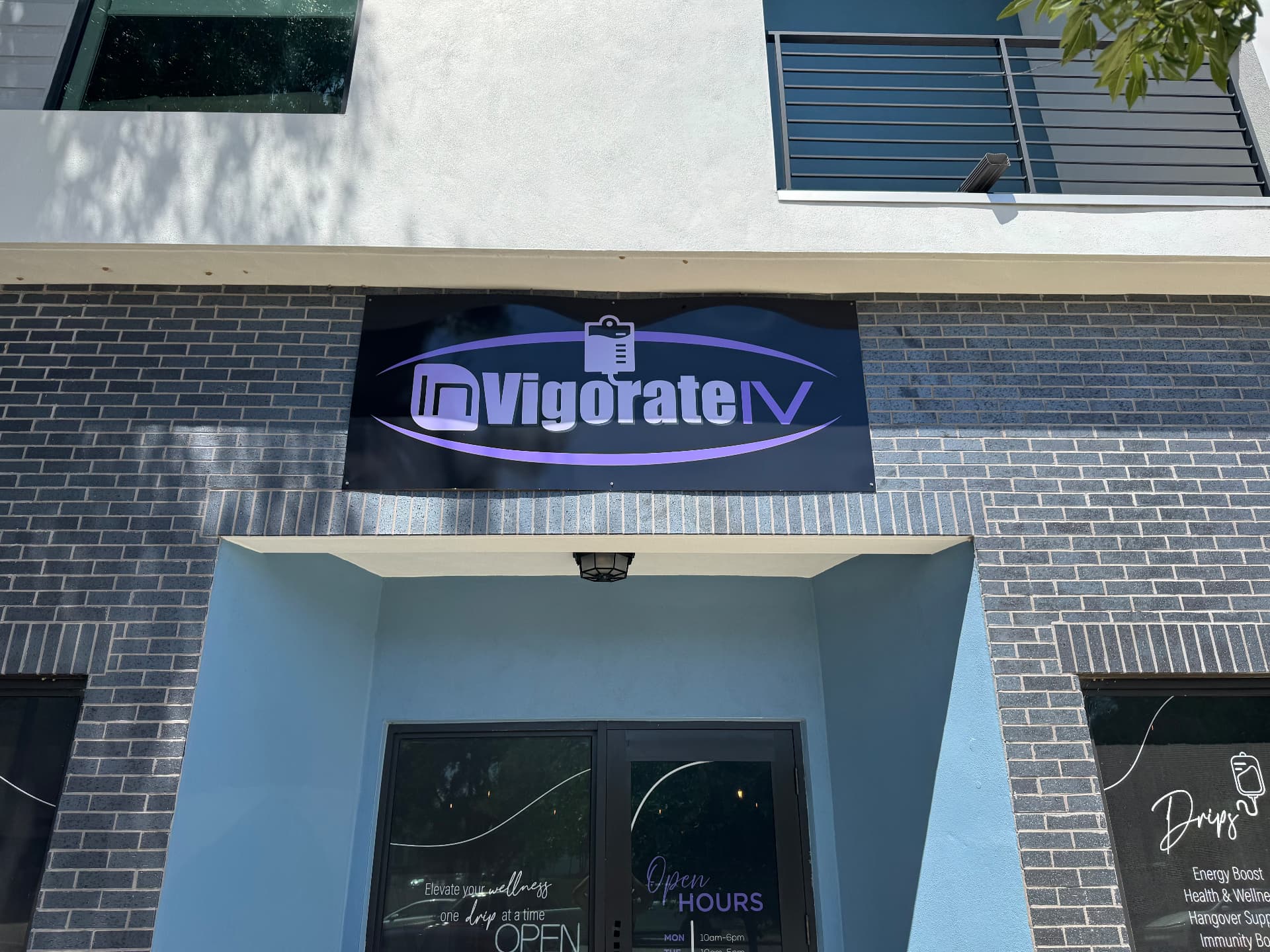 InVigorateIV storefront vinyl banner with purple logo, installed above business entrance in Tampa Bay