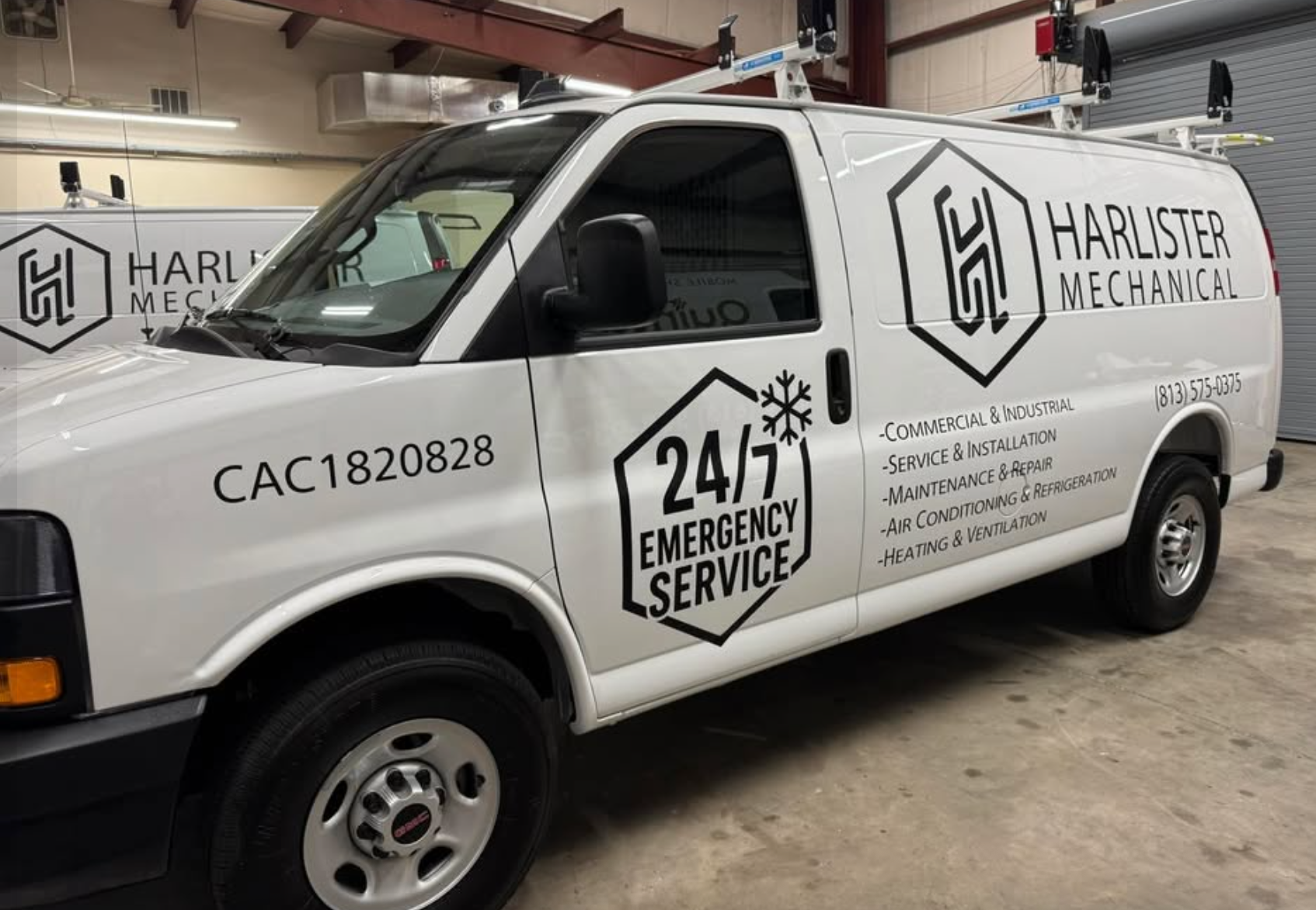 White cargo van indoors with black Harlister Mechanical hexagon logo, service list, 24/7 emergency service icon, and phone number vinyl lettering on side panels, installed by BAPS Signs & Wraps in Oldsmar, FL