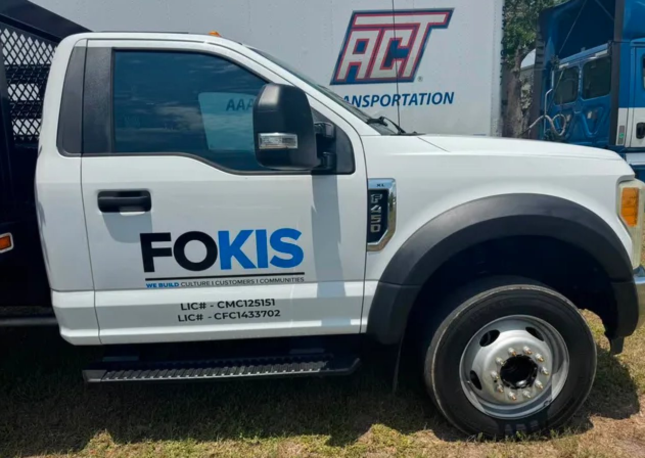 White Ford F-450 truck with FOKIS black and blue vinyl lettering and license info on the door, installed by BAPS Signs & Wraps in Oldsmar, FL